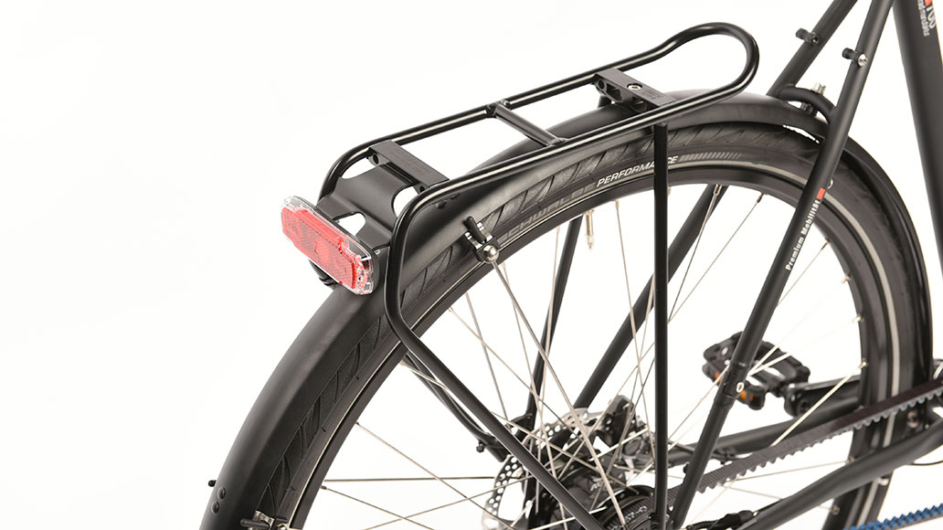 Das Trekkingrad vsf Fahrradmanufaktur T-700 ist ein Verkaufsschlager aus Oldenburg und in drei Varianten erhältlich. Hier die Version mit sportlicher Nabenschaltung, Riemenantrieb und Scheibenbremse. Das ist wartungsarm und servicefreundlich, zuverlässig und zusammen mit dem klassischen, muffenlosen, Stahlrahmen optisch elegant und sportlich schlank. Anwenderfreundlich ist auch der Tretlager-Exzenter, um den Riemen zu spannen. Um die Optik noch ein wenig zu polieren, dürfte der gerne noch dunkler ausfallen. Die Deore-Bremsen versprechen viel Sicherheit, ihre kurzen Hebel passen ins Gesamtbild. Die 160er-Scheiben könnten auf dem Papier etwas knapp bemessen sein und die Entfaltung ist zunächst recht knackig einzuordnen. Optimierungspotenzial besteht beim abstehenden Rücklicht. Steht auf Tempo In leicht sportlicher Sitzhaltung geht es zügig voran, während die Schaltung den Triggerbefehlen direkt und knackig folgt. Die Übersetzung besitzt rasantes Potenzial. Dabei ist sie praktisch gar nicht so herausfordernd und geht auch moderat schiefe Ebenen entspannt an. Es bleibt sogar noch Luft für mehr Kletterei. Das Rad selbst agiert zackig, wendig, agil und bleibt dabei immer sicher. Auch die Reifen lassen es schnell rollen. Dabei ist Asphalt unbedingt das primäre Geläuf. Hier kann und will es sich entfalten. Wald- und Feldwege sollten nicht zu weich und grob sein, denn dafür ist das Rad nicht ausgelegt. Es eignet sich für Stadt, Alltag, sportliches Pendeln und leichte Gepäcktouren. Das Limit setzt der Gepäckträger mit 20 Kilogramm. Theoretisch wären aber ein Lowrider und 125 Kilogramm abzüglich Fahrergewicht anhängbar. Die Bremsen passen perfekt zum Potenzial des Rades. Mit einem bis zwei Kilogramm weniger könnte es seine Sportgene sogar noch ein bisschen besser entfalten. Detailaufnahmen des Trekkingrads vsf Fahrradmanufaktur T-700 im Test: Fazit Das T-700 läuft gerne und schnell. Das wartungsarme, sehr gute Rad ist perfekt für Alltag, sportliches Pendeln und auch für Touren mit leichtem Gepäck geeignet. Positiv: Stabile Laufräder, wartungs- und geräuscharmer Antrieb Negativ: Exponiertes Rücklicht, etwas schmale Schutzbleche Sie interessieren sich für das vsf Fahrradmanufaktur T-700? Mehr Informationen erhalten Sie auf der Website des Herstellers. vsf Fahrradmanufaktur T-700: Technische Details und Informationen Preis 2099 Euro Rad-Gewicht 14,9 kg (mit Pedalen) Zuladung (Fahrer und Gepäck) 125,1 kg Rahmenarten und Größen Diamant: 52, 57*, 62 cm; Trapez: 45, 50, 55, 60 cm *Testgröße Ausstattung des vsf Fahrradmanufaktur T-700 Rahmenmaterial CrMo-Stahl, zweifach konifiziert Gabel Aluminium Schaltung Nabenschaltung Shimano Alfine 11, Alfine Trigger, 11-Gang Entfaltung 2,25– 9,2 m Laufrad Naben: Nabendynamo SP PL-8/ Shimano Alfine S7001-11, Felgen: Schürmann YAK19 Disc, 36-Loch Reifen Schwalbe Marathon Supreme, 28“, 42mm Bremsen hydr. Disc Shimano Deore M6000, 160/160 mm Cockpit Vorbau/Lenker: Levelnine Alu; Griffe: Ergon GP1 Sattelstütze Levelnine Patent Sattel Selle Royal Essenza Lichtanlage B+M Lumotec IQ-XS/ B+M Toplight 2C Sonstiges Riemenantrieb: Gates CDX; Gepäckträger: Racktime Lightit; Schutzbleche: SKS; Ständer: Pletscher Zoom